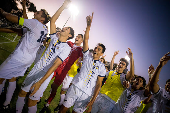 group of mens soccer team players holding their hands up and smiling