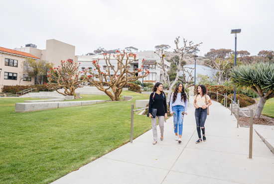 three students walking on the sidewalk