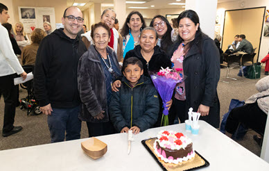 community members gathered around birthday cake