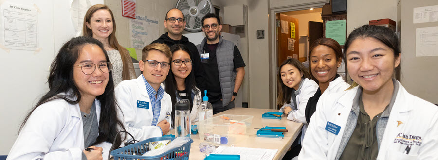 students and physicians gathered around conference table at clinic