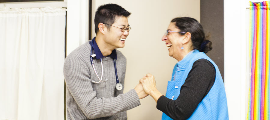 student volunteer clasps patients hands while smiling