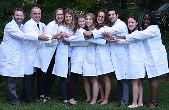 group of 2022 residents in white lab coats hugging